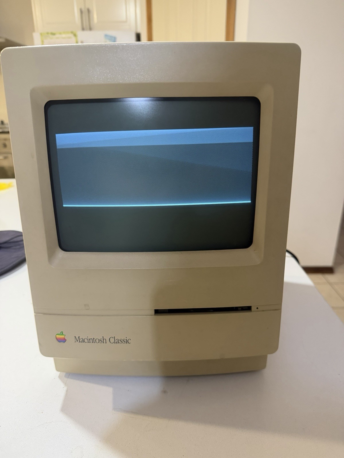The Adelaide Macintosh Classic powered on with a collapsed horizontal band across its monochrome display
